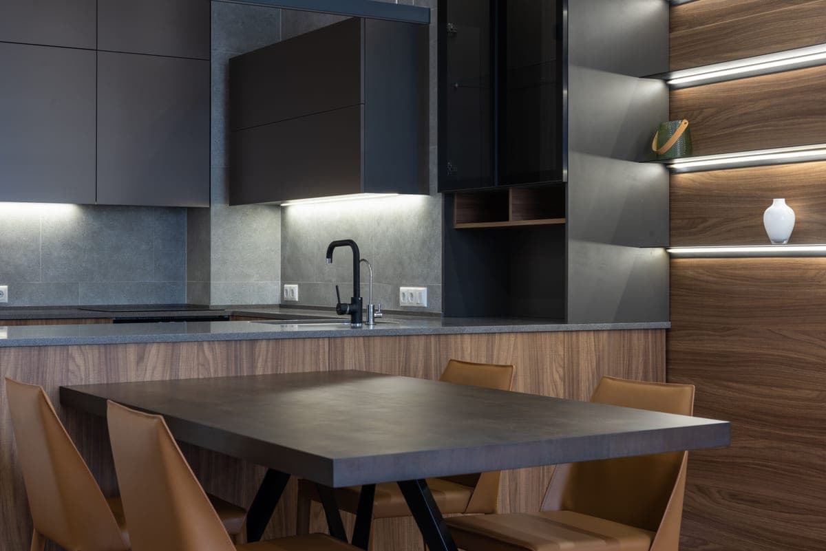 A kitchen counter lit from beneath the wall cabinets after dark