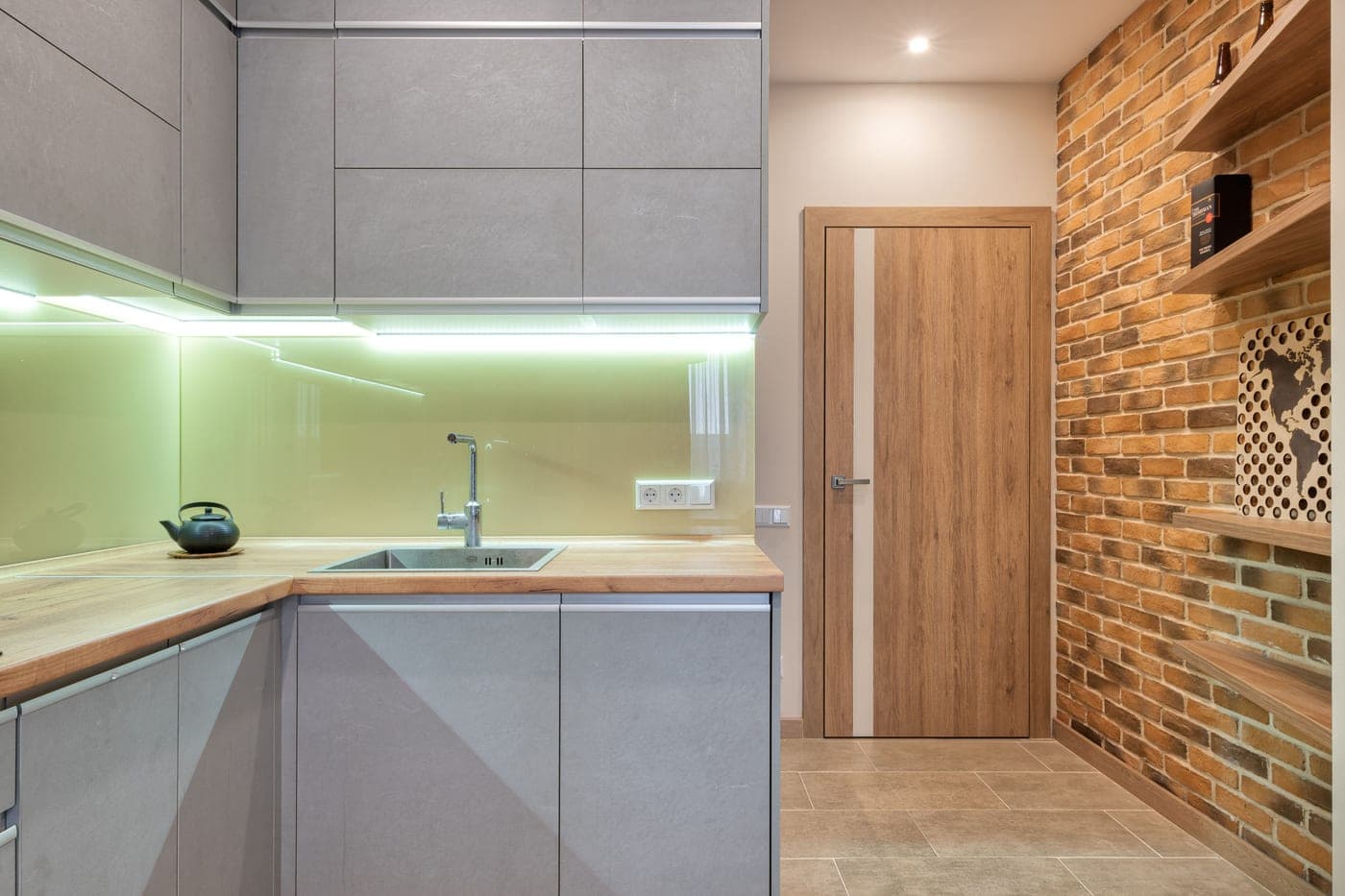 A kitchen counter lit by warm under-cabinet light bars mounted beneath the wall cabinets